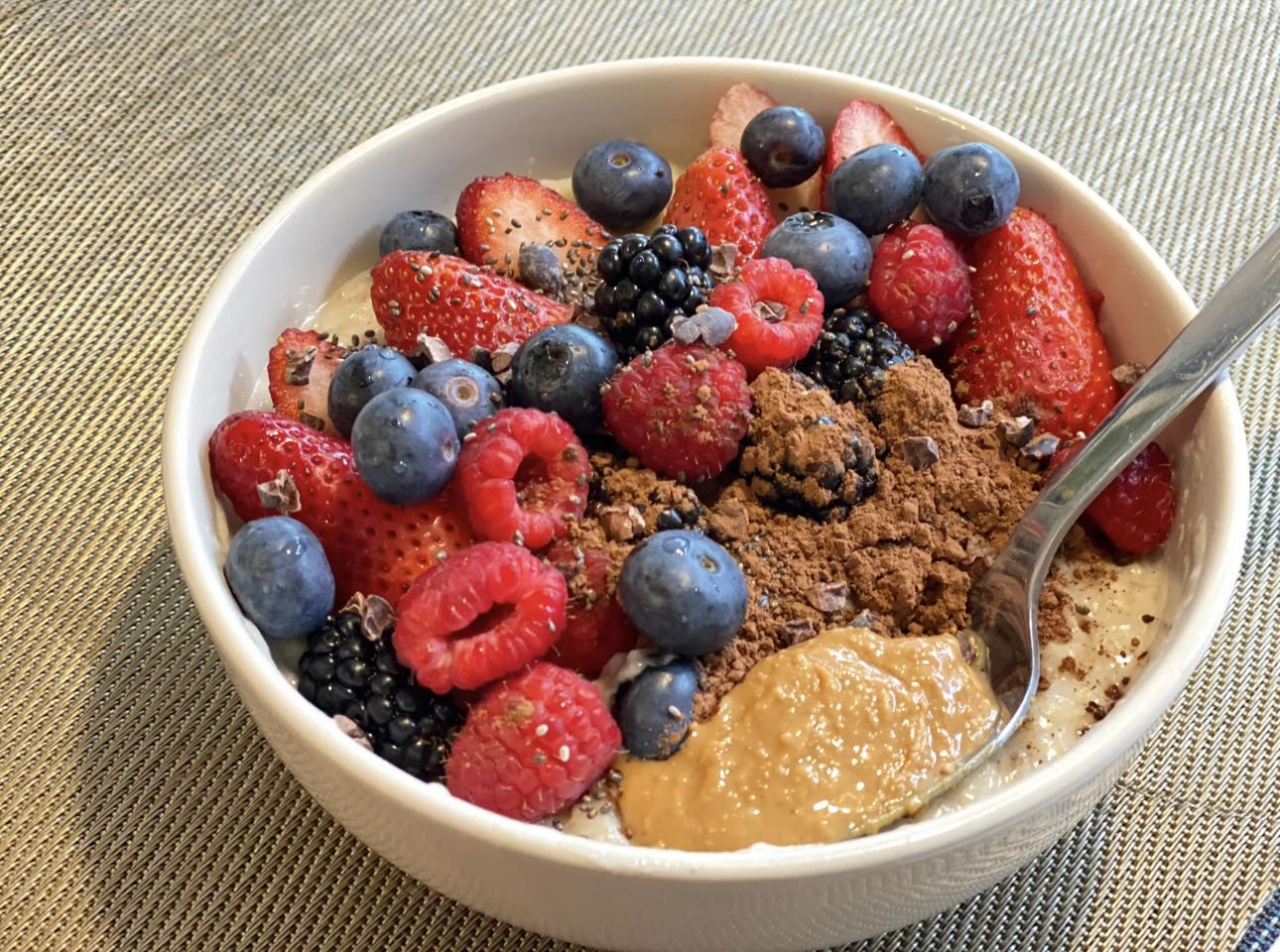 A bowl of high-protein overnight oat with chocolate protein powder, berries, blueberries, strawberries and 1 tbsp honey.
